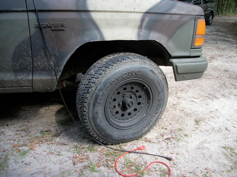 Front fender and tire of a camo-painted Ford Ranger. Another SUV is visible in the background