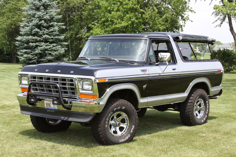 Black and silver Ford Bronco with bull bar and aftermarket wheels parked on grass