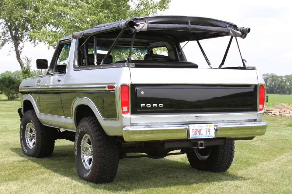 Rear view of a 1979 Ford Bronco with a black soft top and a black tailgate panel. License plate reads BRNC 79