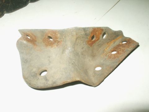 1990 Ford Bronco - A close-up view of a corroded metal bracket with multiple mounting holes.