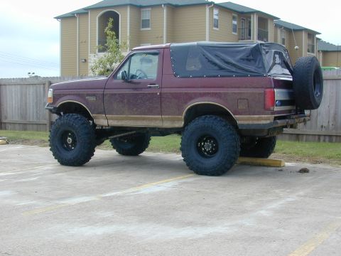 1996 Ford Bronco - This lifted 1996 Ford Bronco features a black soft top and a spare tire mounted on the rear.