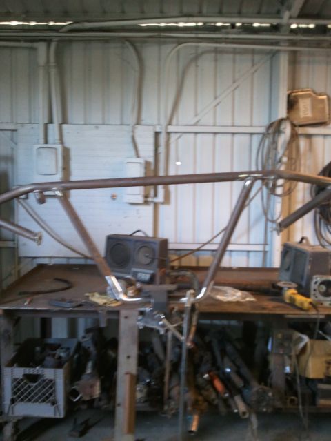 1982 Ford Bronco - A custom roll cage is under construction in a workshop, with tools and parts scattered around.