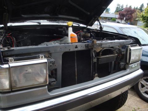 1989 Ford Bronco - The front of a Ford truck is shown with the hood up, revealing the engine and radiator area. A second vehicle is visible behind it.