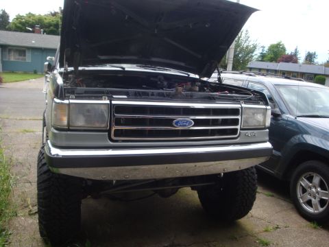 1989 Ford Bronco - Front view of a 1989 Ford Bronco with the hood open, parked next to another vehicle.
