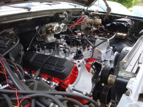 1989 Ford Bronco - Close-up view of a V8 engine, likely modified, with prominent red block and dual throttle body intake.