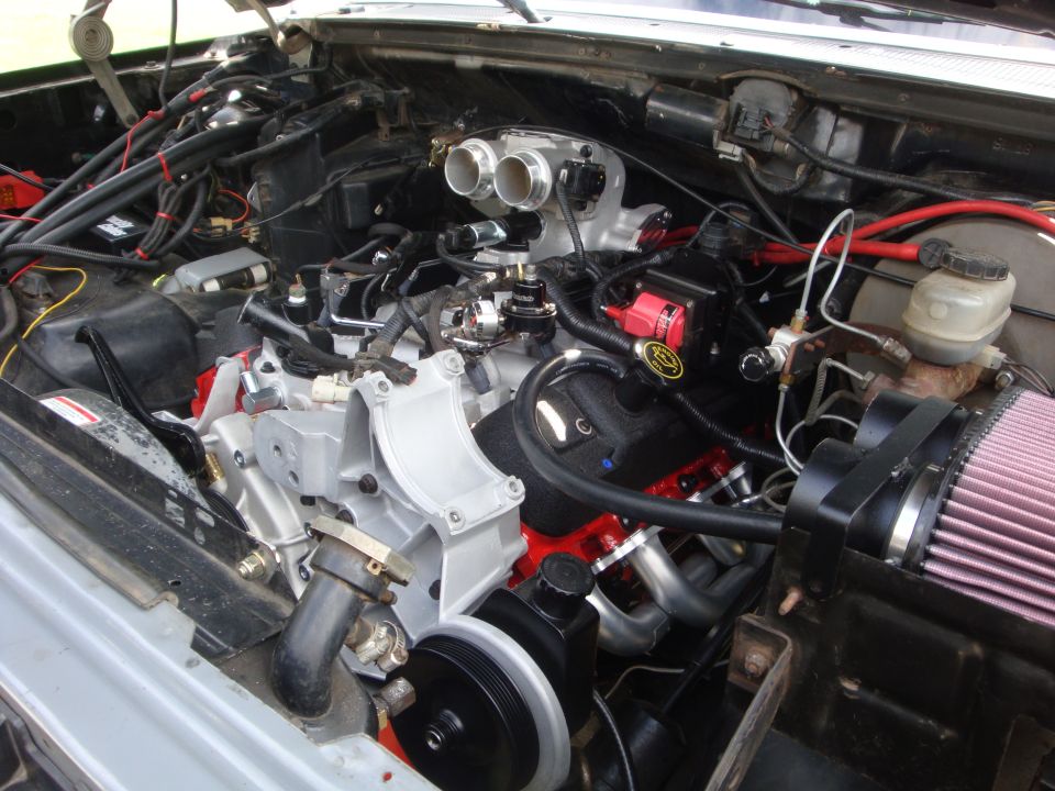 Engine bay with custom intake, headers, and red valve covers. Looks like a Ford V8