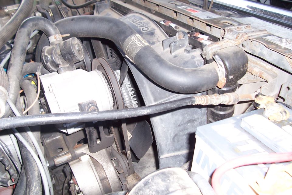 engine bay with radiator, fan, alternator, and hoses visible
