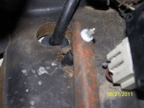 1989 Ford Bronco - Interior view of a vehicle part, showing a rusty rod and a cable. cable. Date stamp visible.