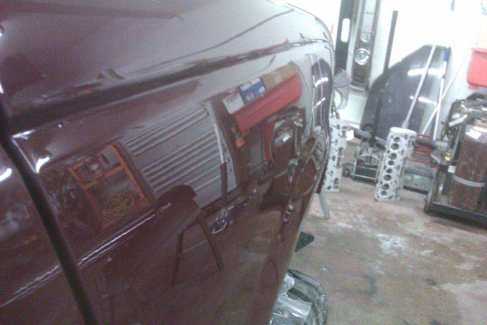 Reflection of garage interior and equipment on a dark red vehicle body panel