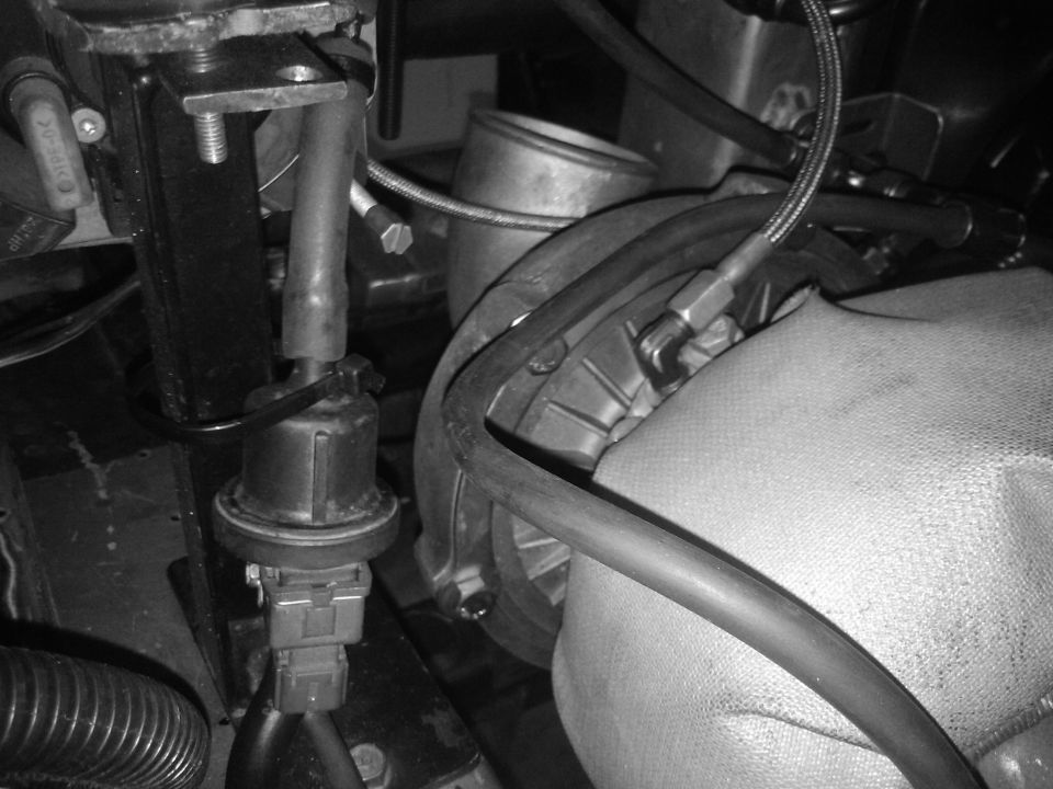 Close-up of engine components including a sensor and hoses