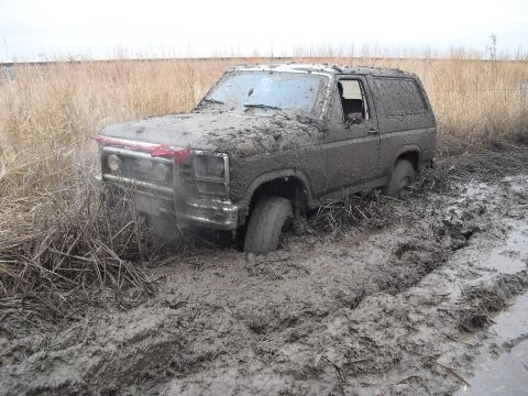 1986 Ford Bronco - This heavily mud-caked Ford Bronco is deeply stuck in a muddy field.