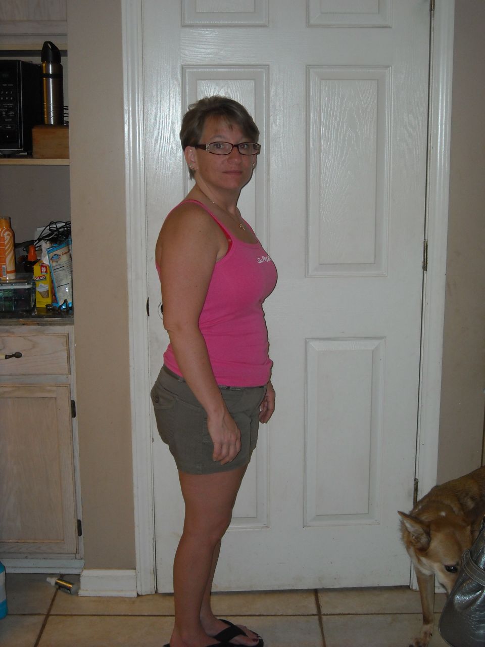 Woman in pink tank top and shorts standing indoors