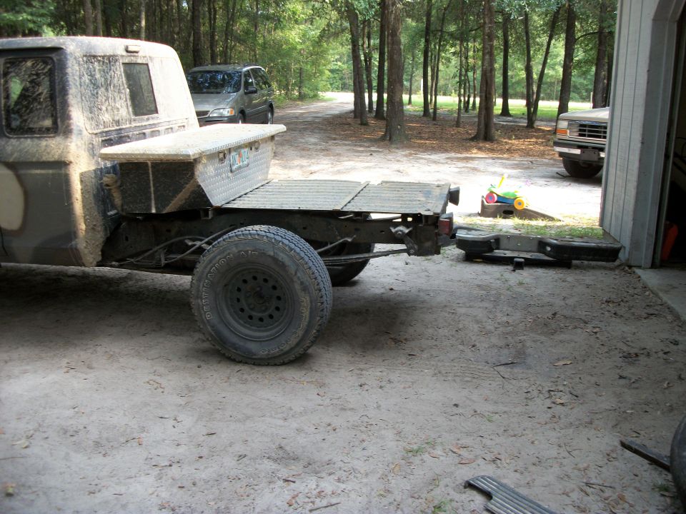 Side view of a flatbed pickup truck with a toolbox; a van and another truck are visible