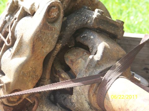 1989 Ford Bronco - Close-up view of heavily rusted metal parts, possibly from a vehicle axle, with a visible date stamp.
