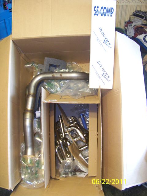 1989 Ford Bronco - Unboxed exhaust system components, including bent pipes and smaller metal pieces, with brand labels on packaging.
