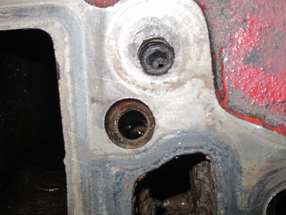 Close-up of an engine block with a bolt and a hole showing internal components