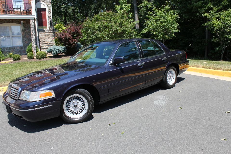 1999 Ford Crown Victoria sedan, dark blue, parked outside a building