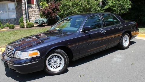 1999 Ford Crown Victoria - This dark blue sedan has a distinctive chrome grille and wire-spoke wheels.