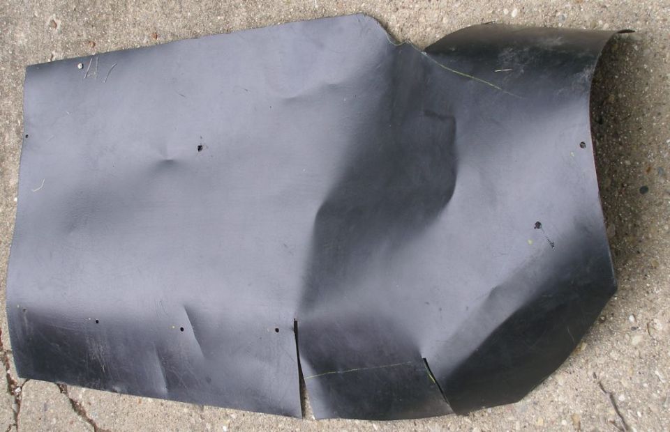 Black plastic fender liner with dents and cuts