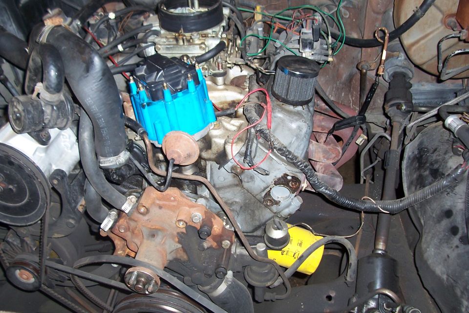 Engine bay with blue distributor cap, carburetor, and oil filter
