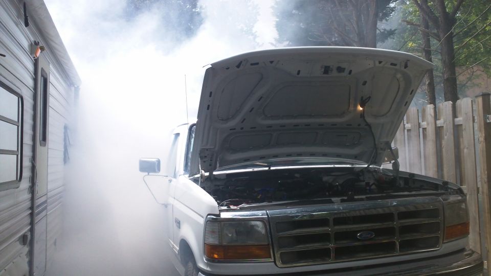 1996 Ford Bronco front view with hood open, emitting smoke