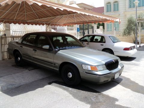 2001 Mercury Grand Marquis - A 2001 Mercury Grand Marquis is parked under a covered carport, with another vehicle visible behind it.
