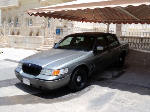 2001 Mercury Grand Marquis - A 2001 Mercury Grand Marquis is seen parked under a beige awning in front of a building.