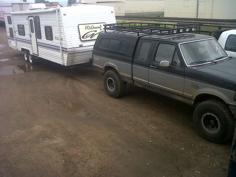 1994 Ford F-150 - A 1994 Ford F-150 pickup truck tows a Wildwood travel trailer on a dirt lot.