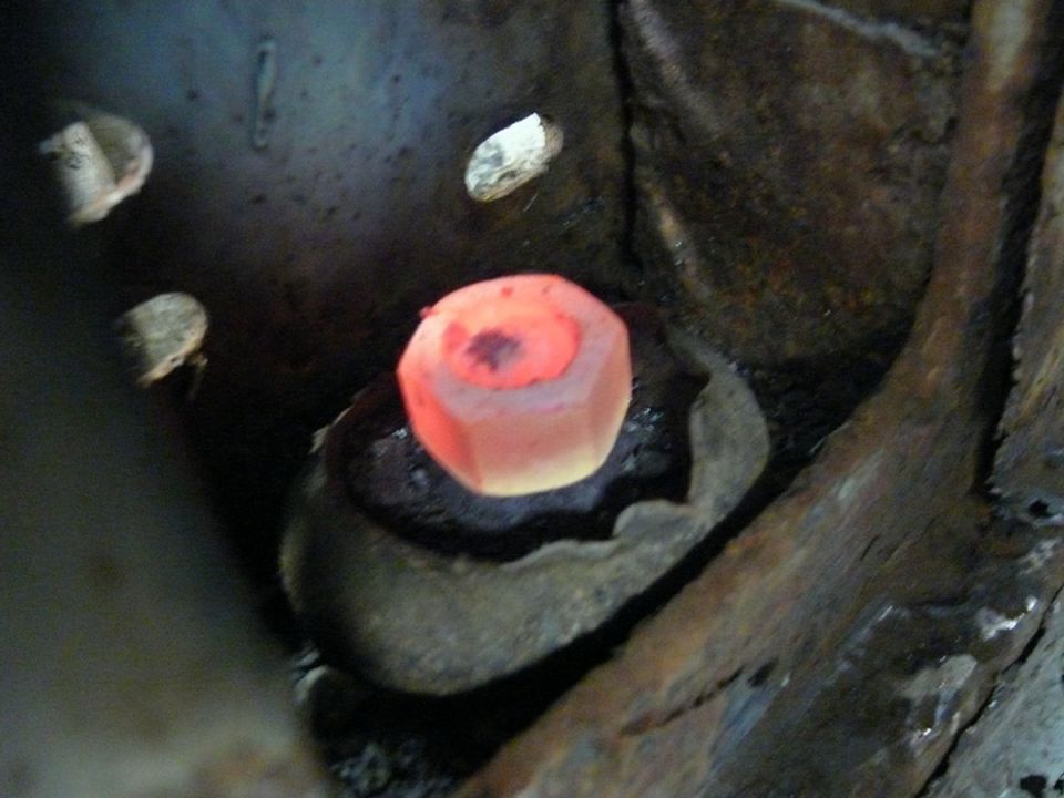 Glowing red bolt head in rusty metal