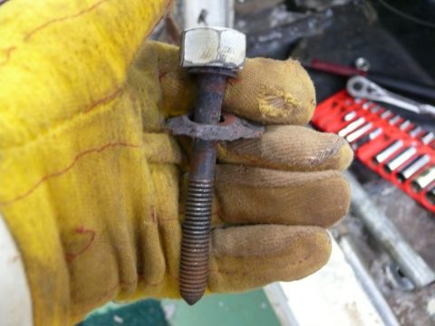 1976 Chevrolet Corvette - A gloved hand holds a rusty bolt and washer, with a toolbox in the background.