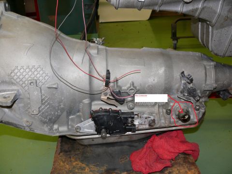 1976 Chevrolet Corvette - Close-up of an automatic transmission component, showing wiring and a red cloth on a workbench.