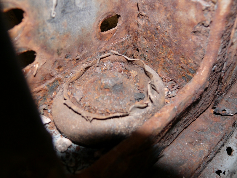 Close-up of heavily rusted metal frame part with a bolt head visible