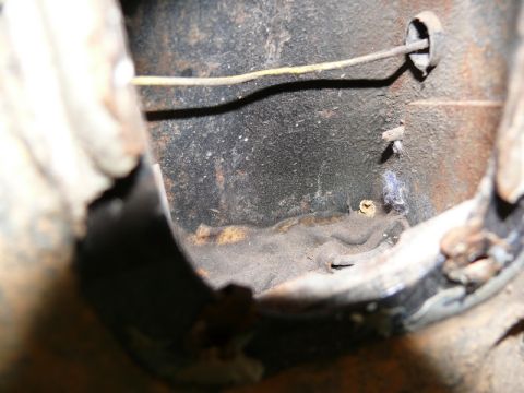1976 Chevrolet Corvette - A close-up view of a rusty metal component, possibly from a vehicle's undercarriage, with a wire and a small screw visible.
