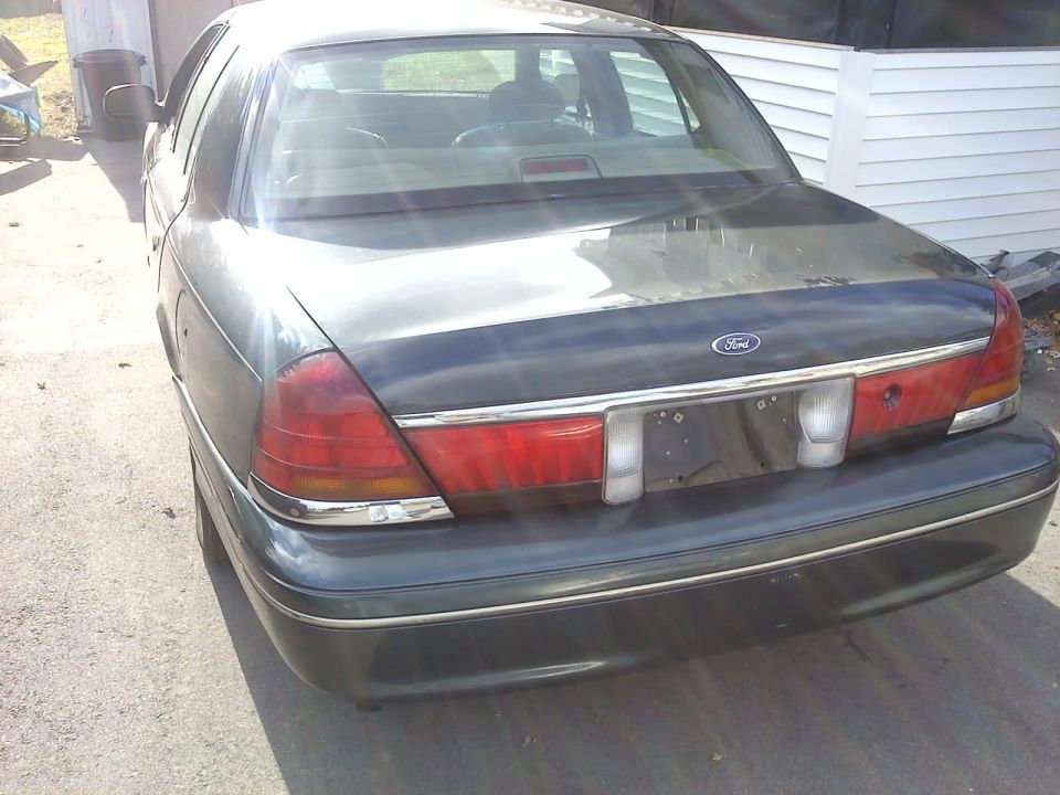 Rear view of a dark-colored 1998 Ford Crown Victoria parked outside