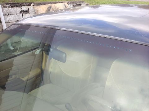 1998 Ford Crown Victoria - View of the car's interior, showing beige seats and a line of small lights at the top of the windshield.