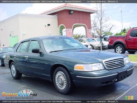 1998 Ford Crown Victoria - A dark green Ford Crown Victoria police interceptor is parked in a lot next to other vehicles.