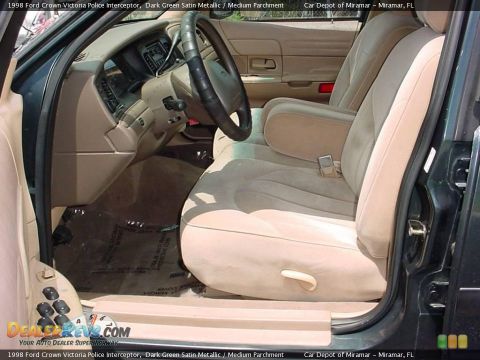 1998 Ford Crown Victoria - The interior of a 1998 Ford Crown Victoria Police Interceptor is visible, tan cloth seats and a dark dashboard.