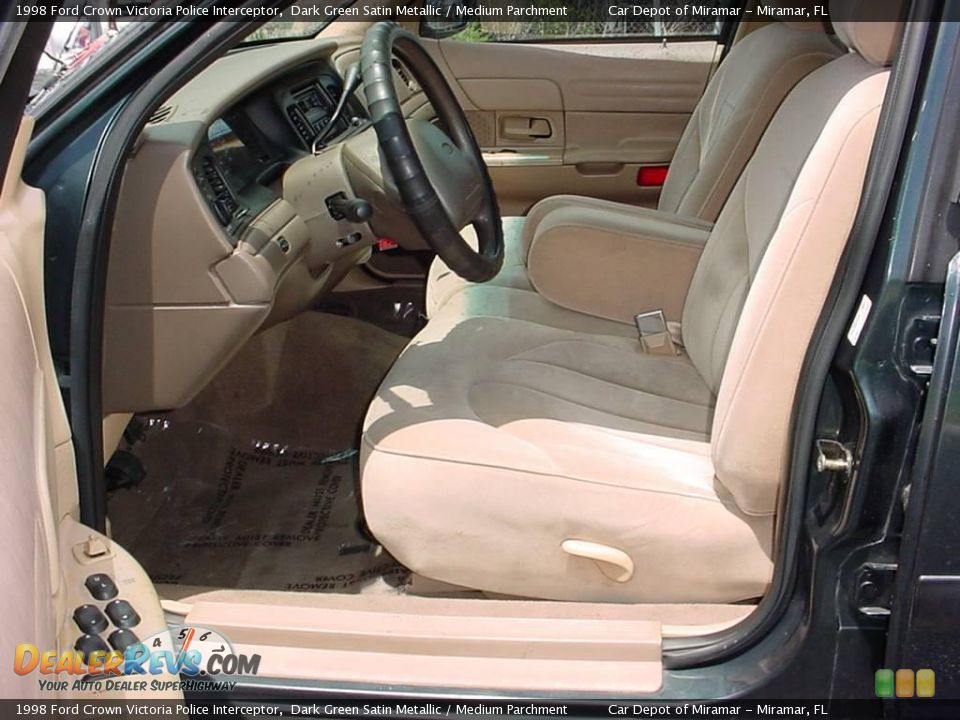 Interior of a 1998 Ford Crown Victoria Police Interceptor, showing tan cloth seats, dashboard, and steering wheel