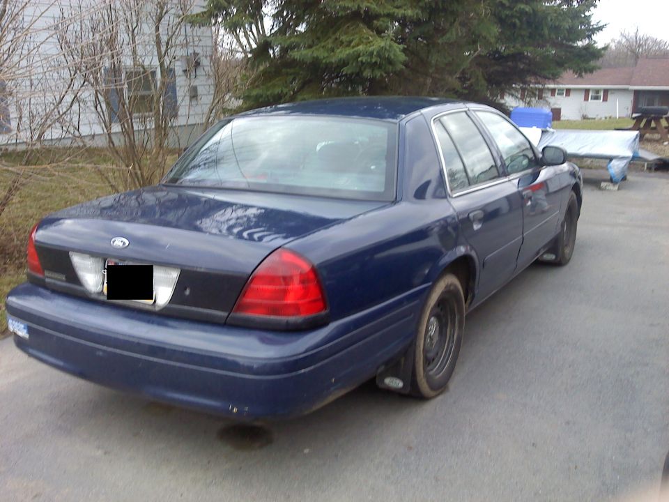 Dark blue sedan parked in a driveway. Rear view shows taillights and trunk