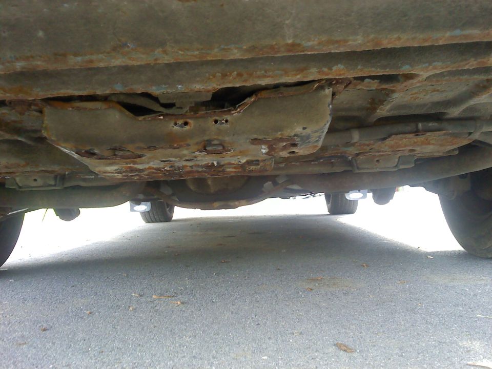 Heavily rusted vehicle underbody with holes in floor panels