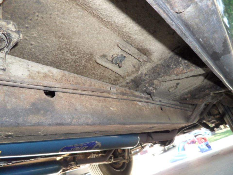 Underside of vehicle showing frame and exhaust system with blue shock absorber