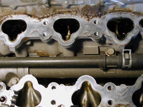 1996 Ford Probe - Close-up view of engine intake manifold ports, showing internal wear and a connecting pipe.