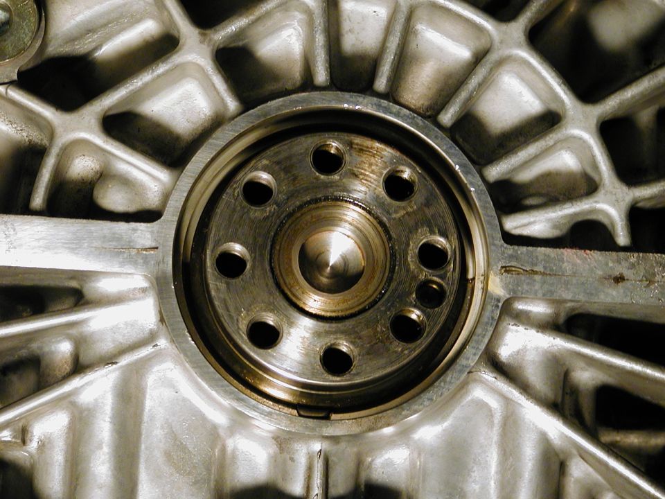 Close-up of a metal engine component with a circular opening and bolt holes