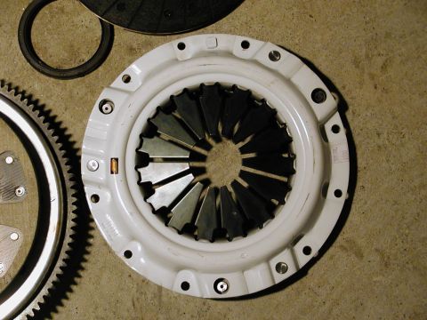 1996 Ford Probe - A clutch pressure plate and flywheel are laid out on a concrete surface, with a ring seal nearby.
