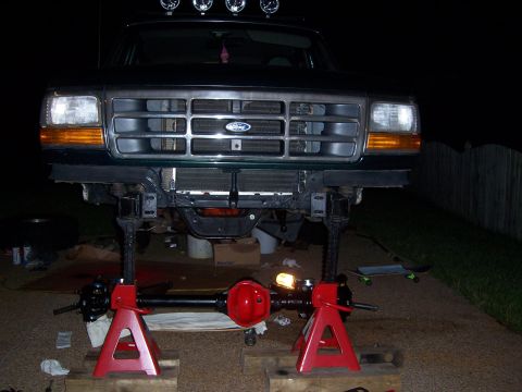 1992 Ford Bronco - Front view of a 1992 Ford Bronco undergoing maintenance, with the front axle removed and supported by jack stands.