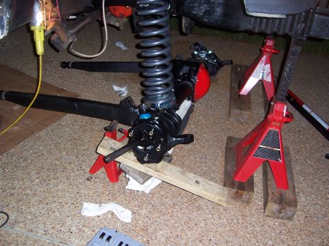 1992 Ford Bronco - The front suspension of a vehicle is disassembled and supported by jack stands.