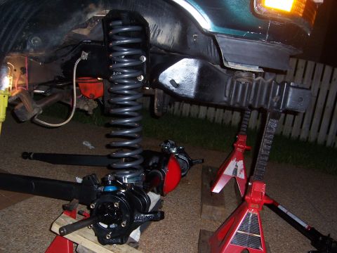 1992 Ford Bronco - Close-up of a vehicle's front suspension system undergoing maintenance, with parts laid out.