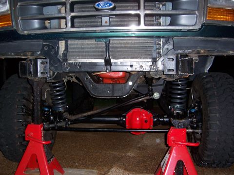 1992 Ford Bronco - Front suspension and undercarriage of a 1992 Ford Bronco, supported by red jack stands.