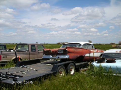 1958 Ford Fairlane - A vintage 1958 Ford Fairlane is loaded onto a trailer, with other vehicles visible in the background.