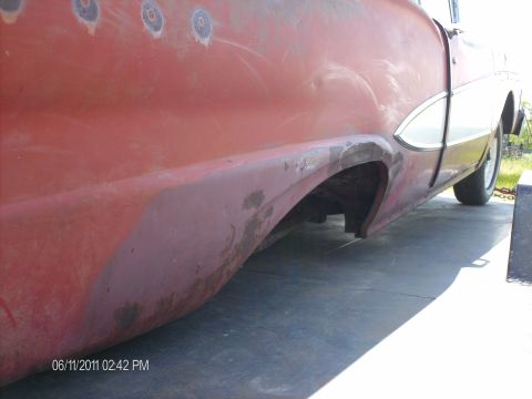1958 Ford Fairlane - Side view of a red 1958 Ford Fairlane's rear quarter panel, showing rust and repair areas.